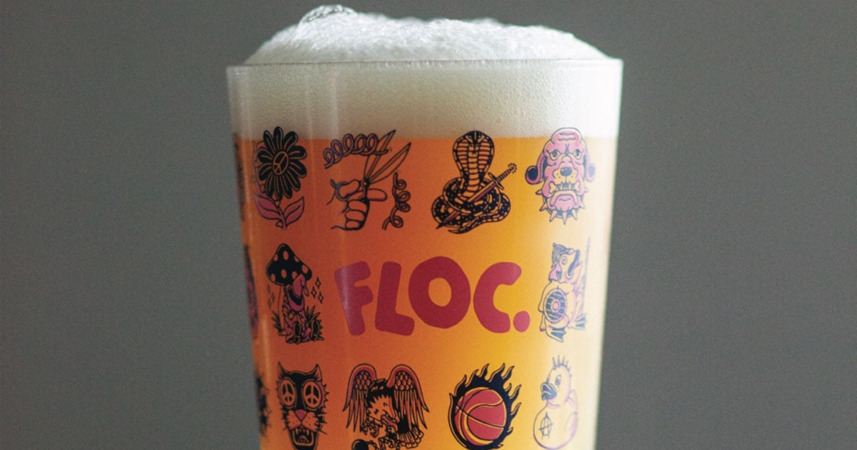 A pint of beer in a colourful branded Floc glass is full and looks refreshing. The vibrant design of the glass and branding reflect the unique and high-quality experience of enjoying Floc's specialty beers